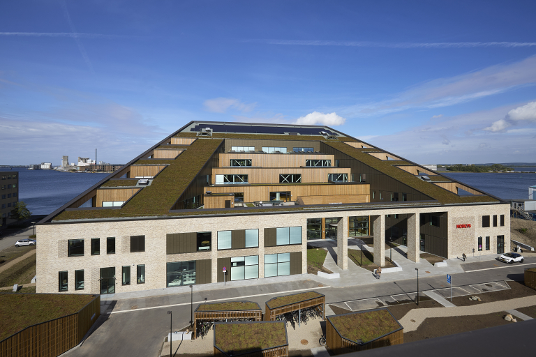 Moderne Norlys-bygning med trappeformet træfacade og grønne tage ved vandet
